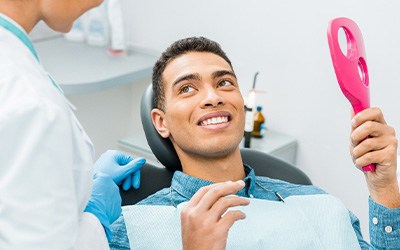 Patient smiling at dentist with pink mirror