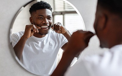Man smiling while flossing teeth at restaurant