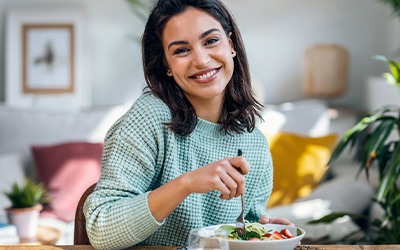 Woman smiling while eating lunch at home