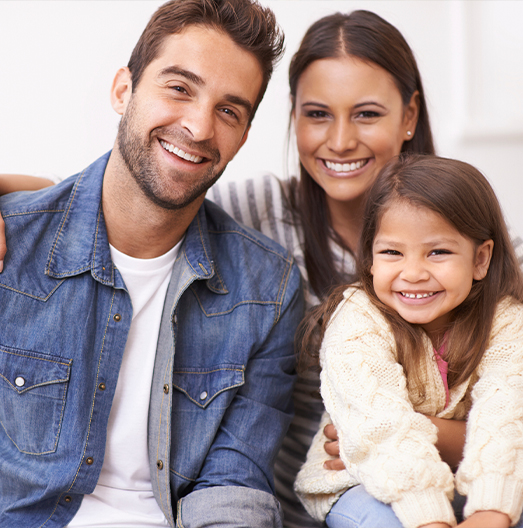 Family of three smiling on couch