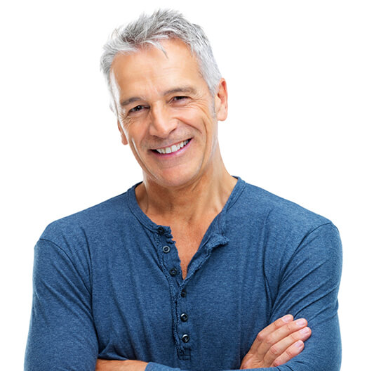 Smiling older man in blue shirt standing with arms crossed