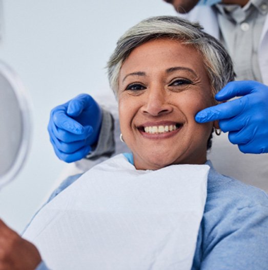 Closeup of woman smiling while holding handheld mirror