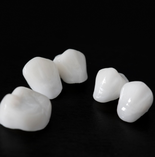 Five white dental crowns against black background