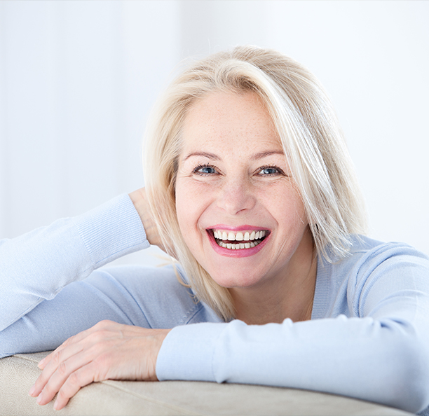 Smiling woman with dental implants in Northbrook sitting on couch