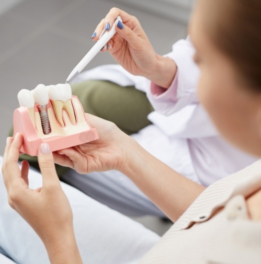 Dentist showing a patient a dental implant model