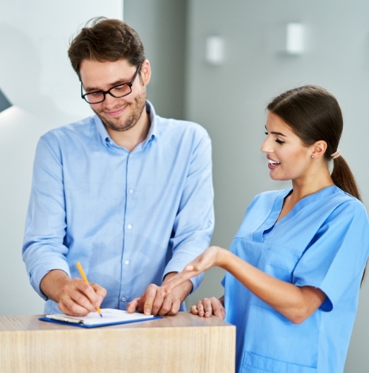 Dental patient signing form on clipboard