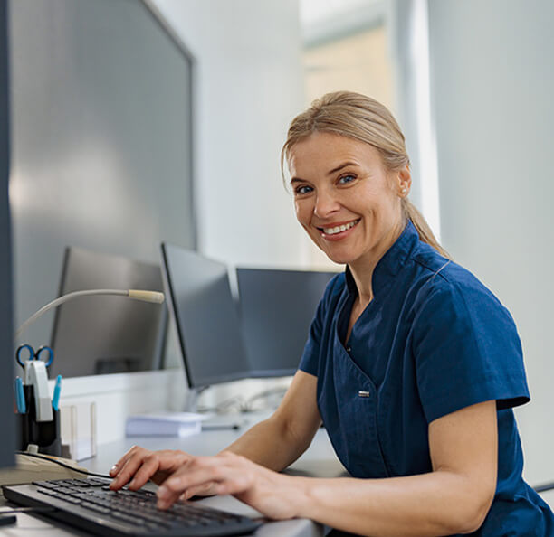 Smiling Northbrook dental team member typing on computer