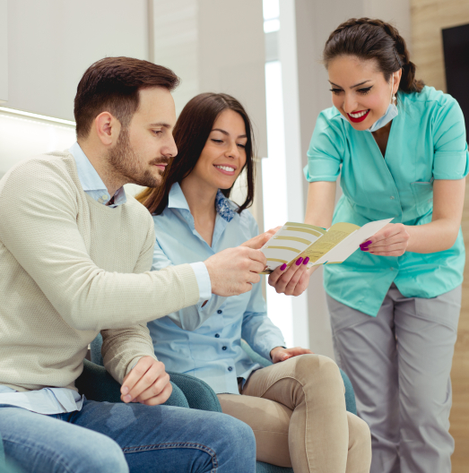 Dental team member showing a pamphlet to two patients