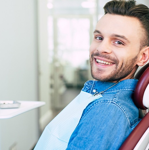 Man in denim jacket sitting back in dental chair after gum recontouring in Northbrook