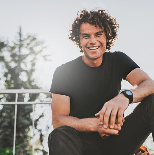 Man with curly hair sitting on top of bleachers 