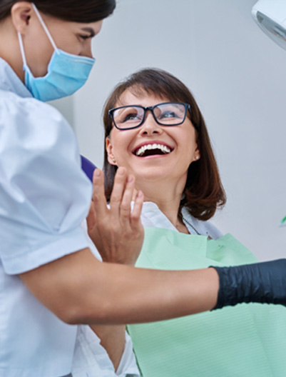 Woman smiling with dentist while reviewing X-ray