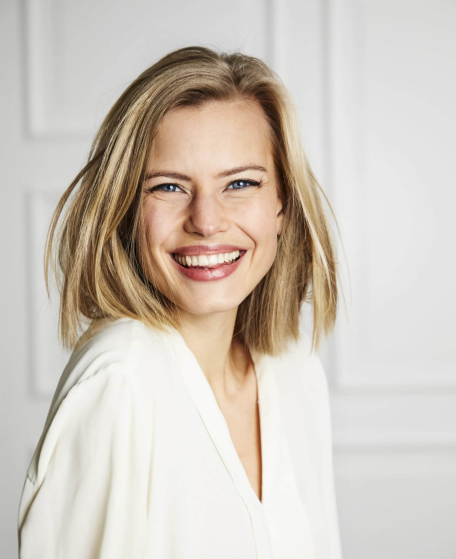 Blonde woman in white blouse grinning