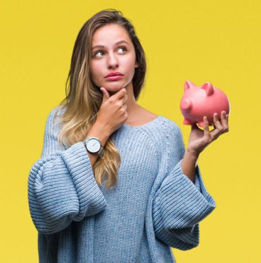 Woman wearing curious expression, holding piggy bank