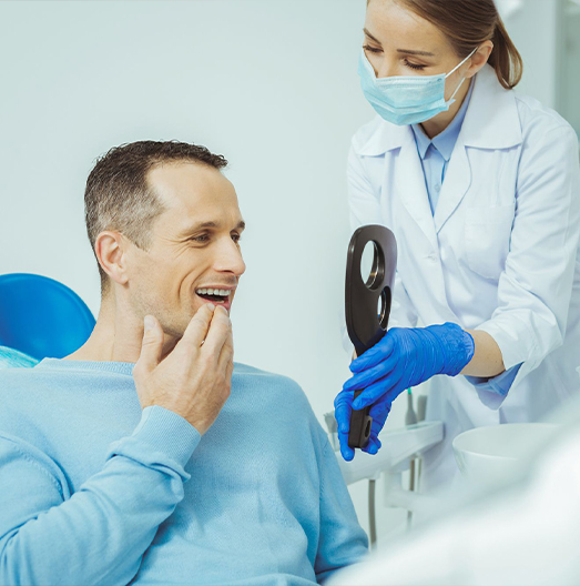 Dental patient looking at his smile in mirror