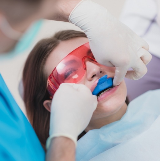 Young woman receiving fluoride treatment from dentist