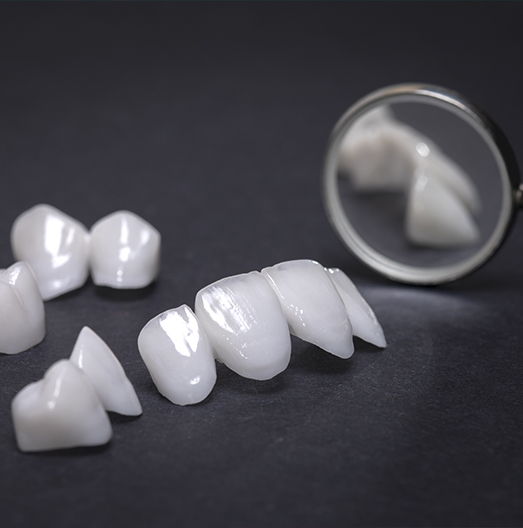 Row of dental crowns next to dental mirror