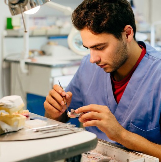 Dental tech carefully designing a dental crown 