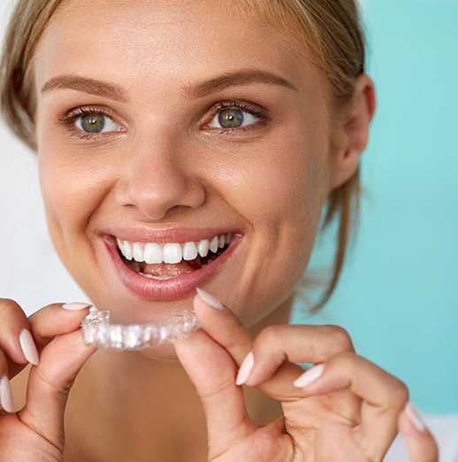 Smiling patient holding teeth whitening tray
