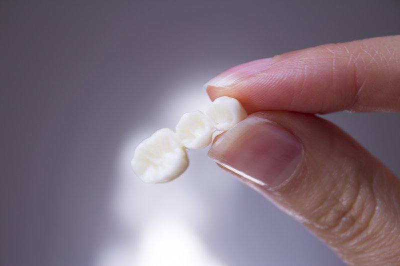 A closeup of a hand holding a dental bridge